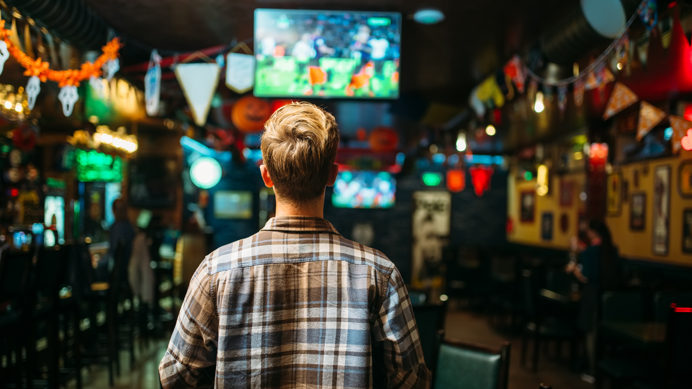 Man staring at multiple TV screens showing different sports games.