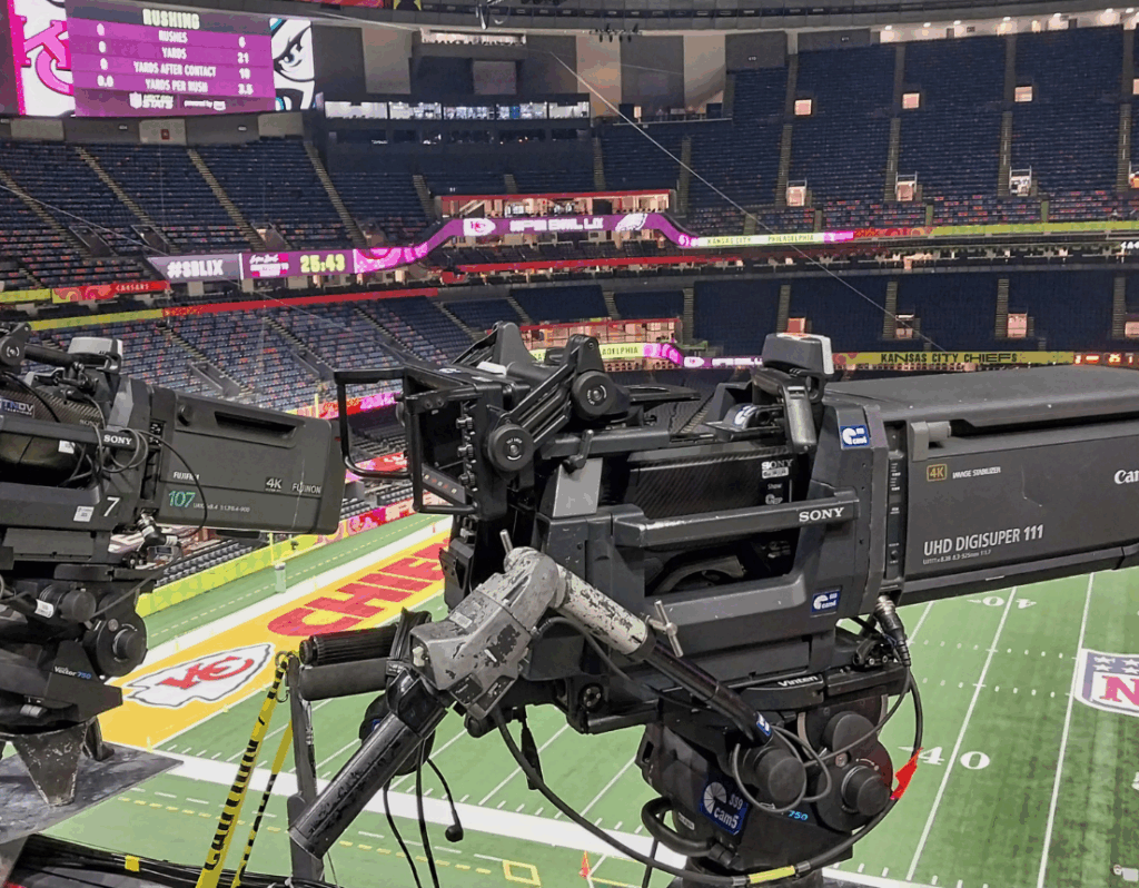 TV cameras prepare for NFL game before crowds arrive.