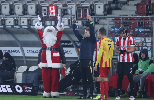 Referee dressed as Santa Clause on sideline during game.